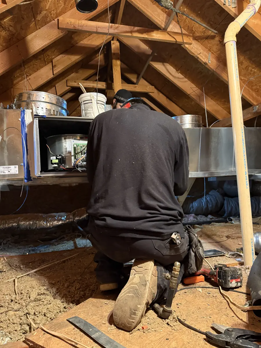Frymire technician working on a furnace installation in a hot attic