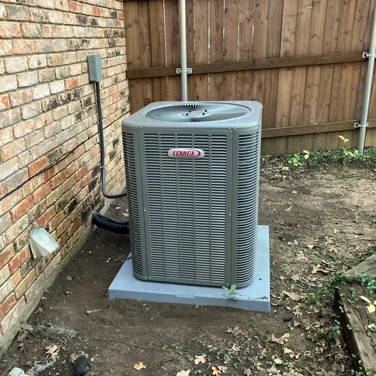 Completed Lennox condensing unit installed on a level pad beside the home