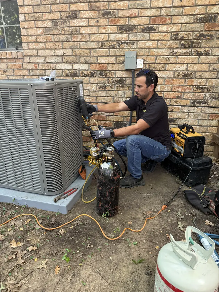 Frymire technician brazing refrigerant line connections at a new outdoor condensing unit