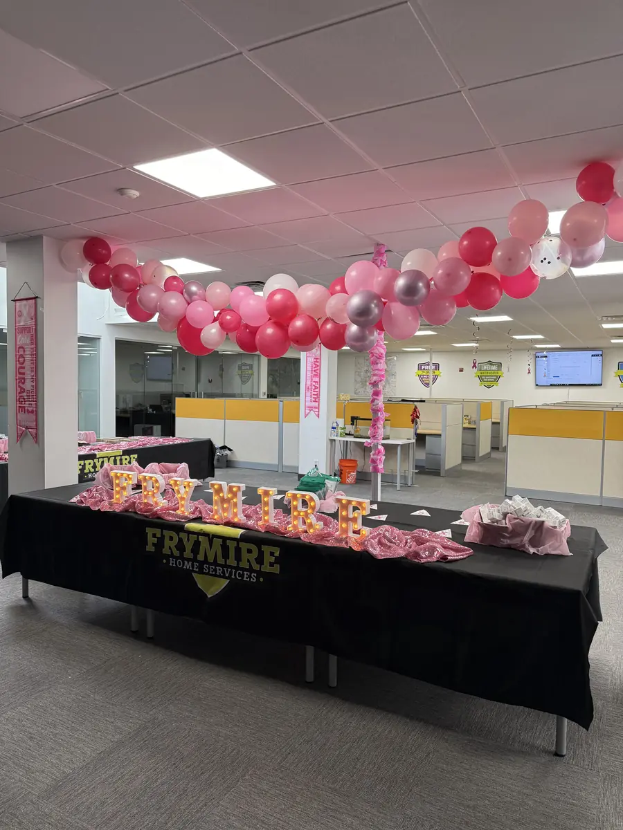 Office decorated in pink with balloon arch and long tables of HOPE Kit supplies