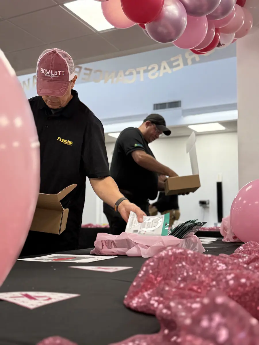 Two Frymire employees filling HOPE Kit boxes beside pink balloons
