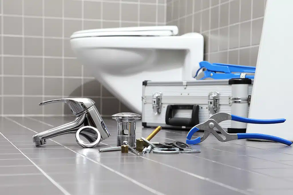 Plumbing equipment on a bathroom floor used to complete faucet repair services.