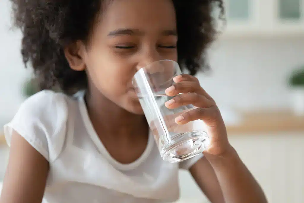 Child drinking a glass of clean water that has been filtered with a whole-home filtration system.