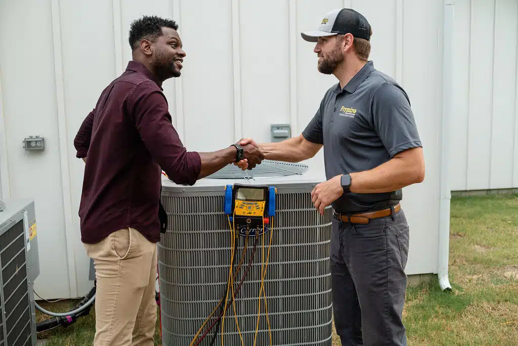 frymire hvac technician shaking hands by HVAC with a homeowner