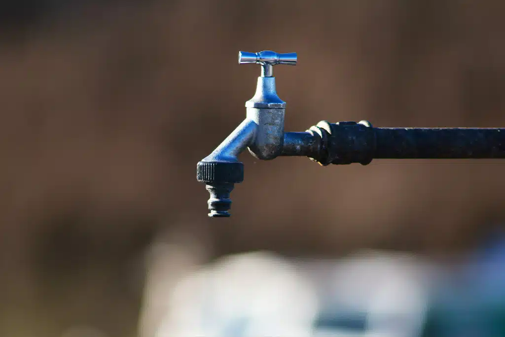 A close-up of an outdoor faucet with blurred background
