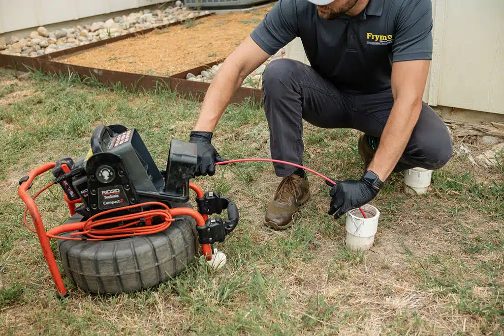 Frymire Home Services employee checking for blockage in sewer drain from outdoor access point in ground.