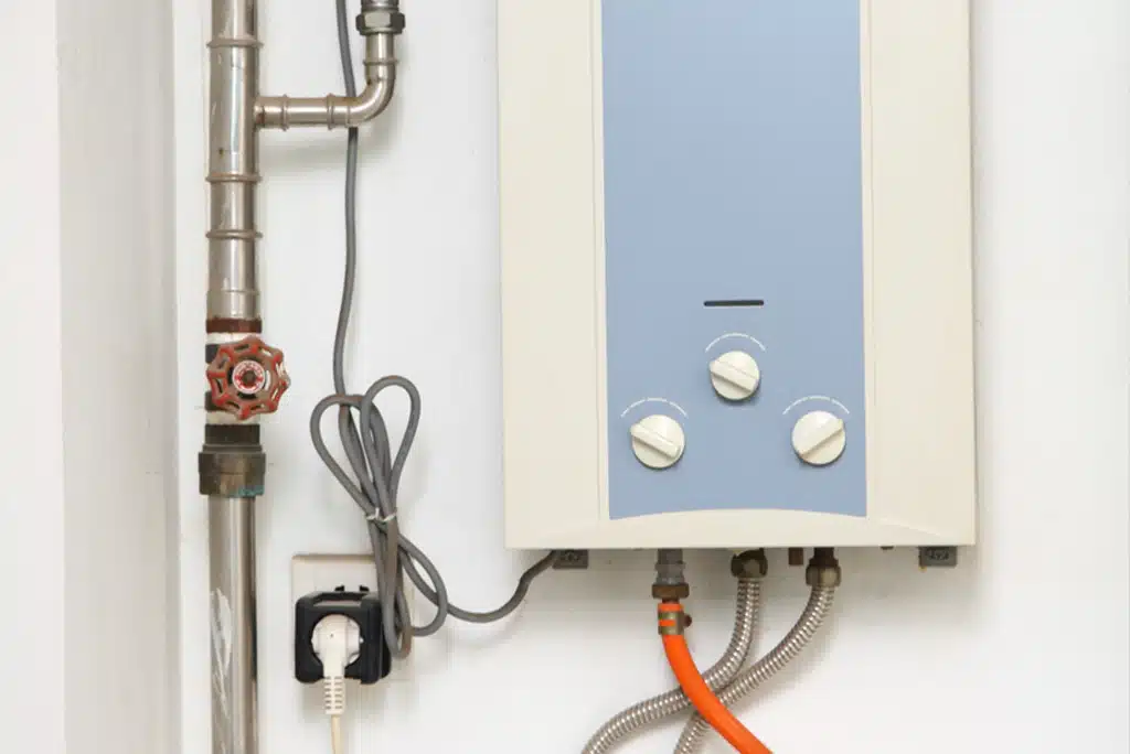 A close-up of a tankless water heater installed on a white wall.