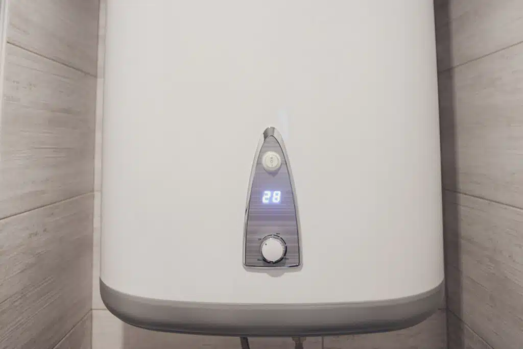 A white tankless water heater installed in a utility closet.